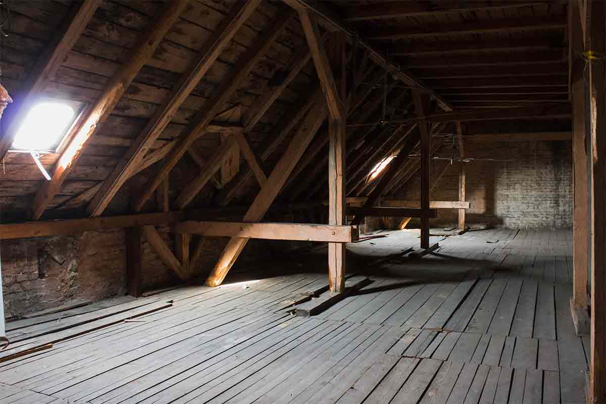 Empty, unfinished attic with wood floor and exposed wood beams