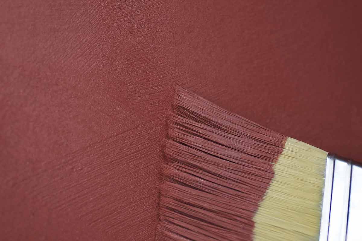 Close-up image of paint brush and brushstrokes in red paint