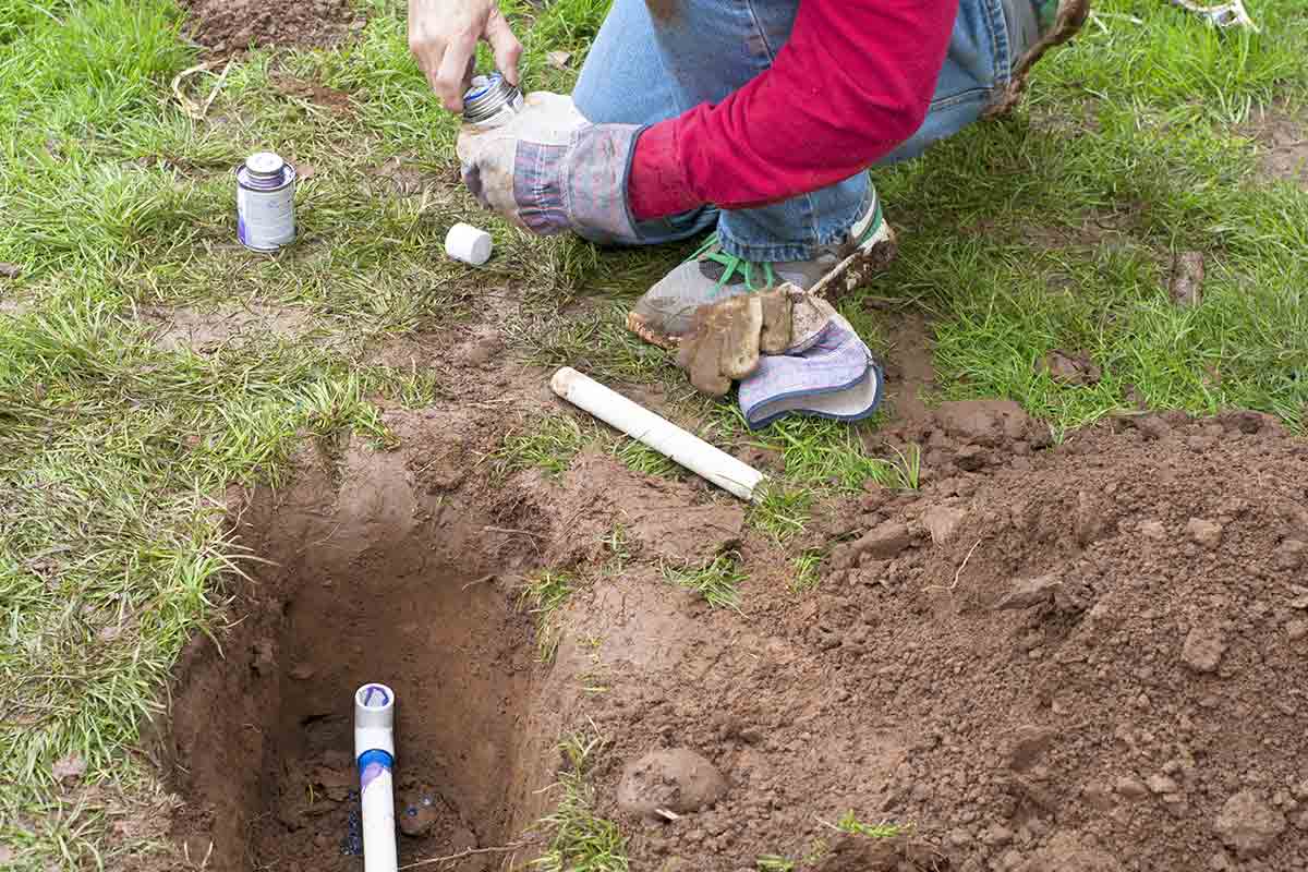 Sprinkler system installer connecting underground piping for new irrigation system