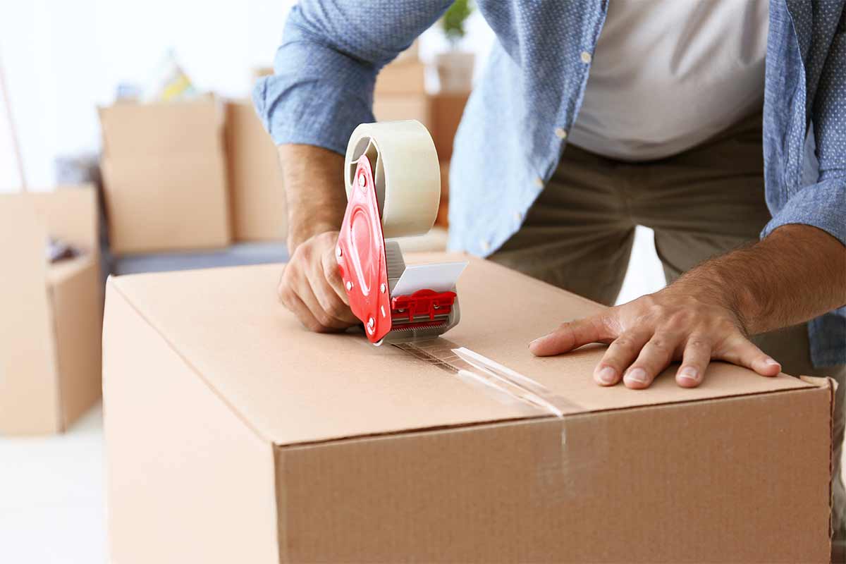 man taping bottom of cardboard box