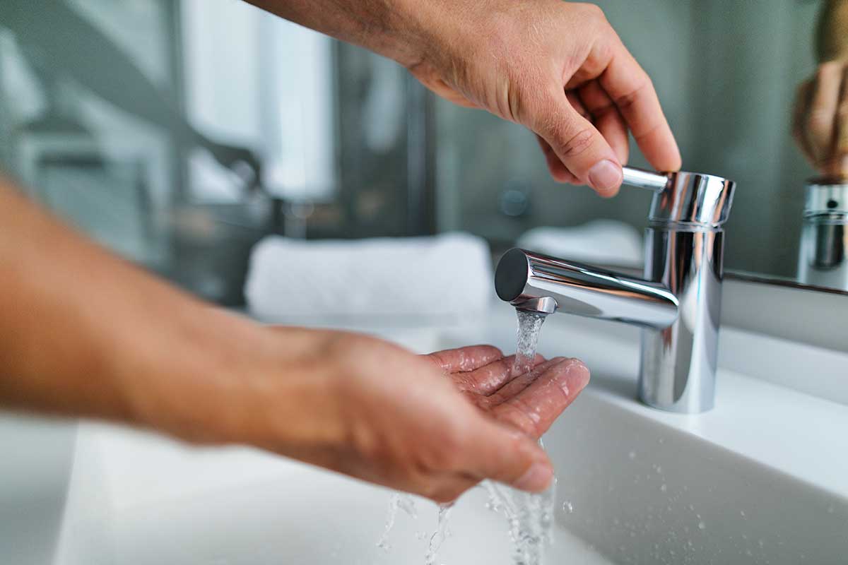 Close-up of a man washing his hands under a running faucet