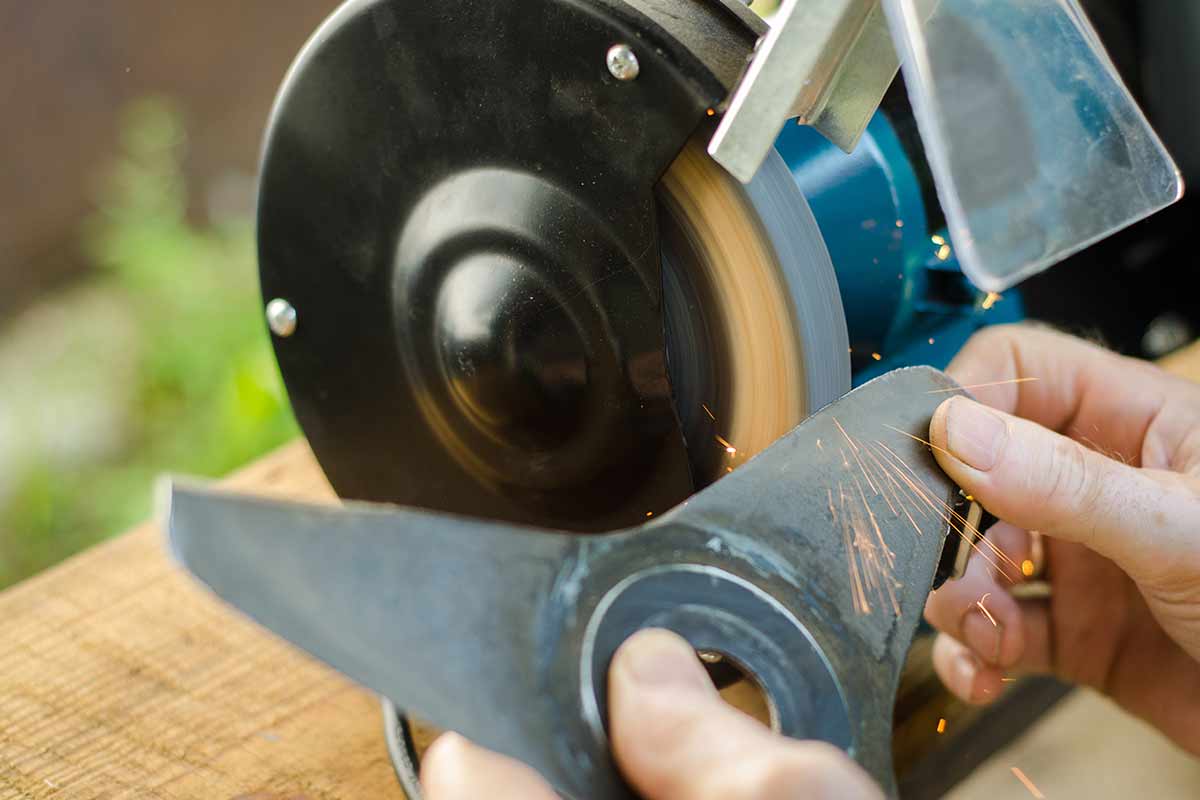 man sharpening lawn mower blades