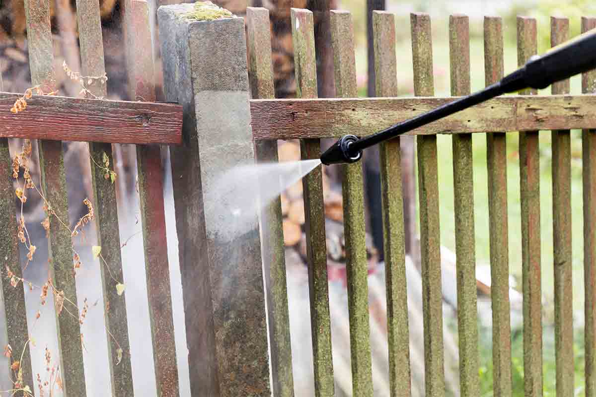 pressure washer cleaning dirt from wood fence