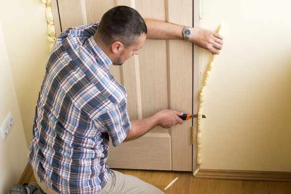 man cuts off excess foam from door