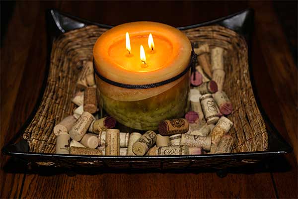 centerpiece with candle resting on used wine corks in wicker tray