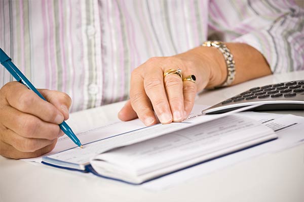 s [close-up of woman's hands writing a check