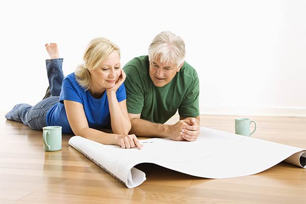 couple lying on floor looking at blueprints