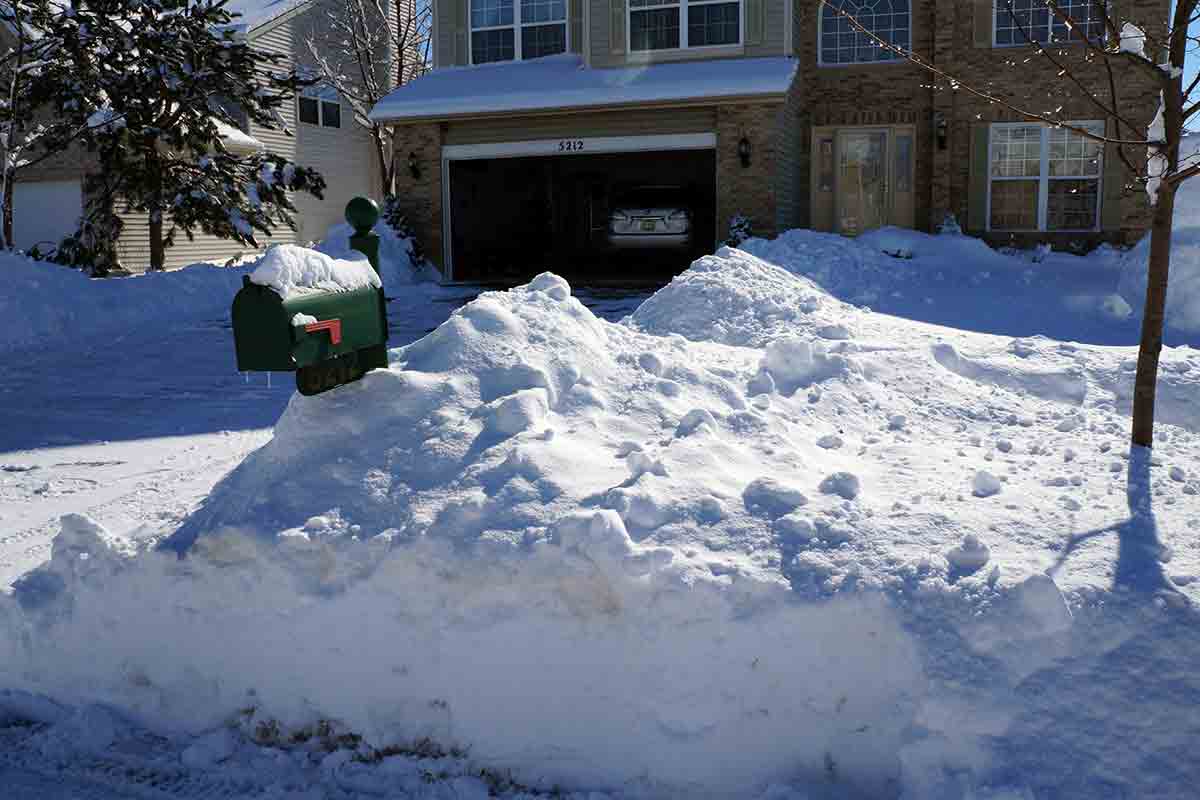 snow piled high in front yard of house