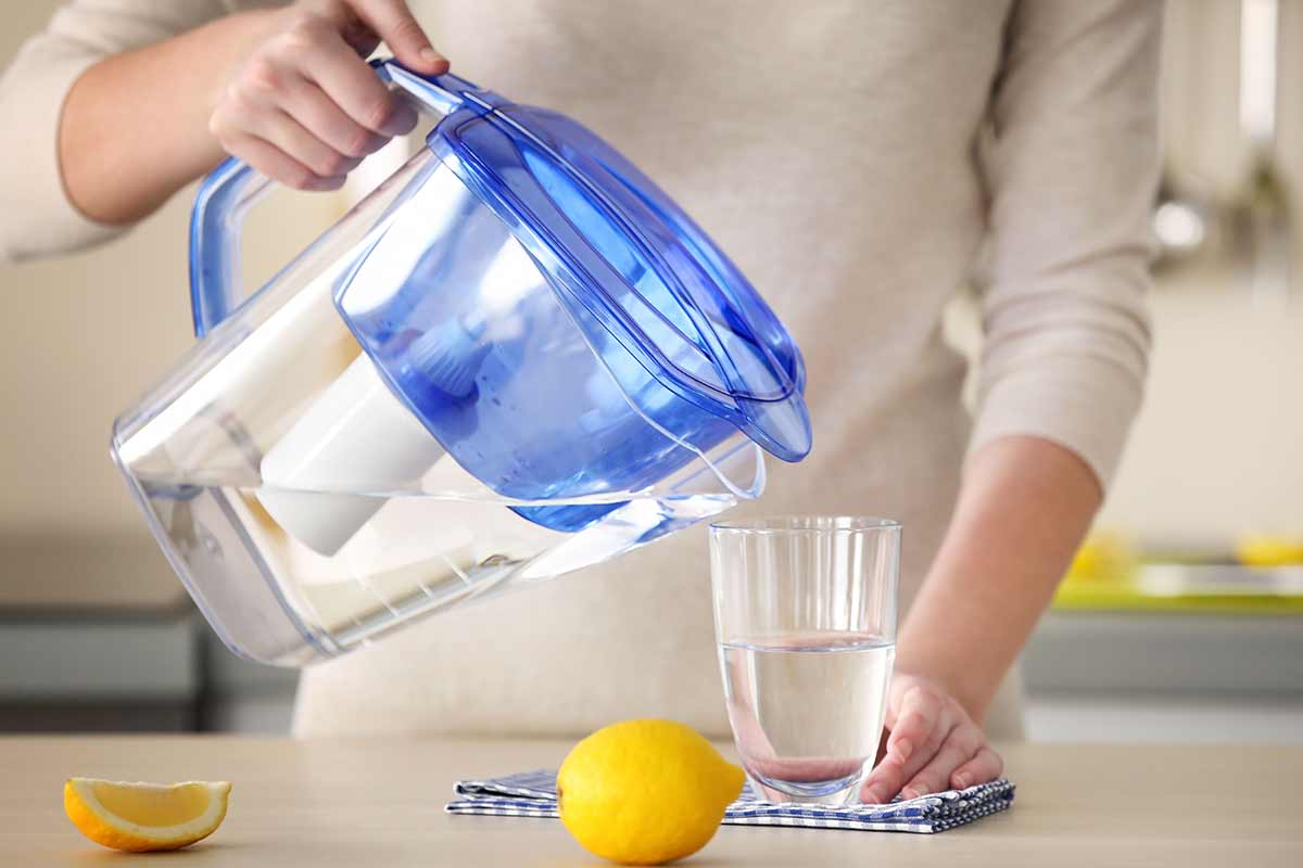 woman pouring water from pitcher filter