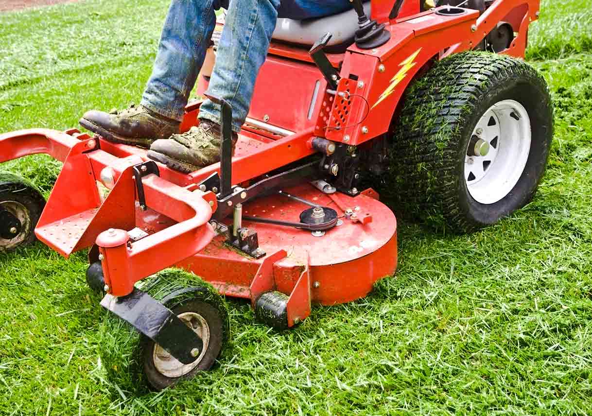 Man riding lawn mower with grass on tires