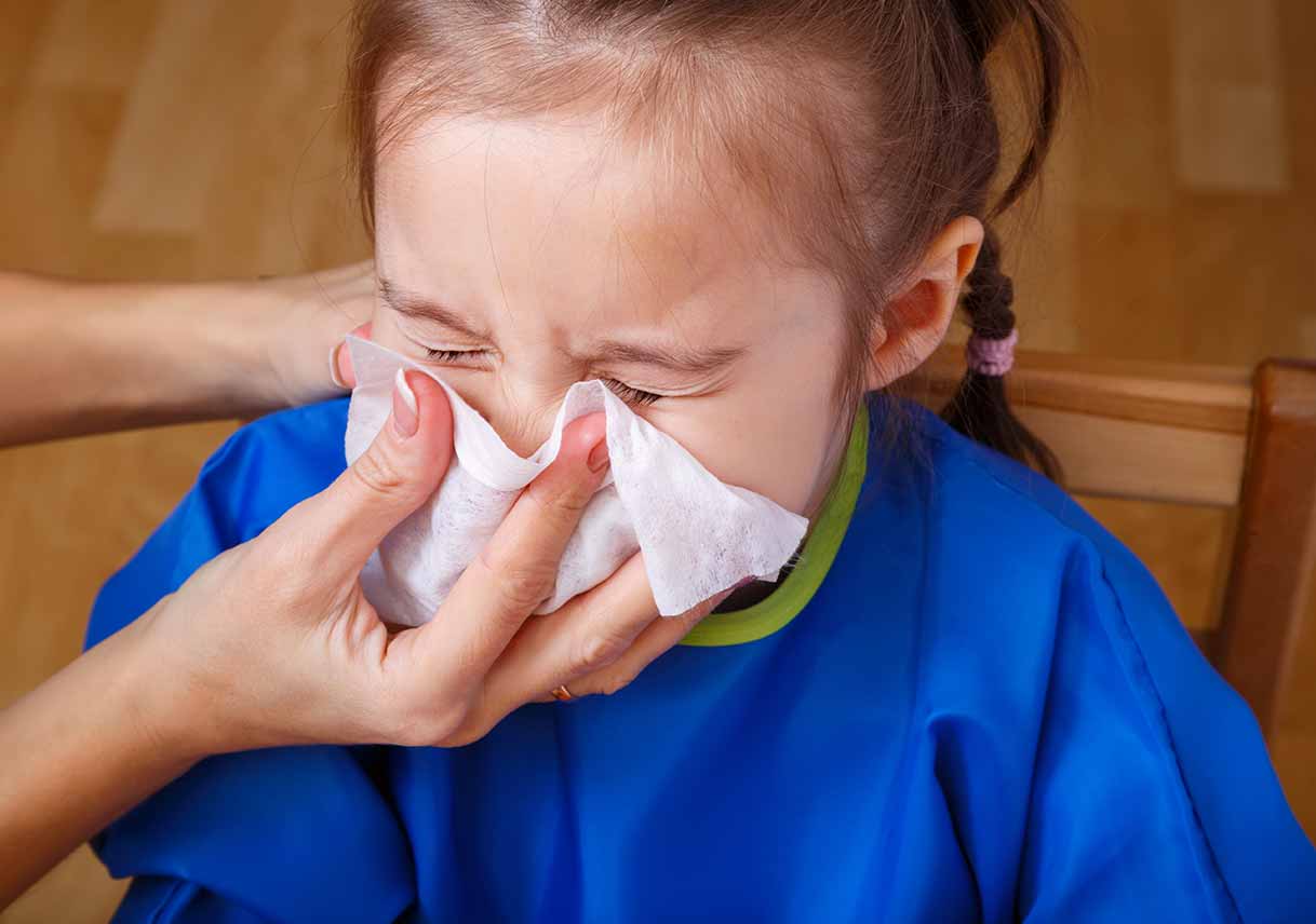 parent helping kid blow nose