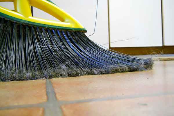 close-up of a broom sweeping tile floor