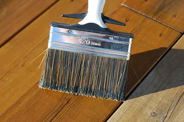 close-up of brushing stain on wooden deck