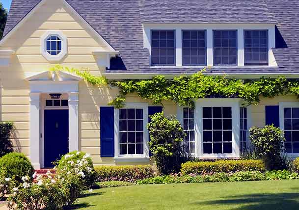 Pale yellow cottage-style home with blue door and shutters and white trim