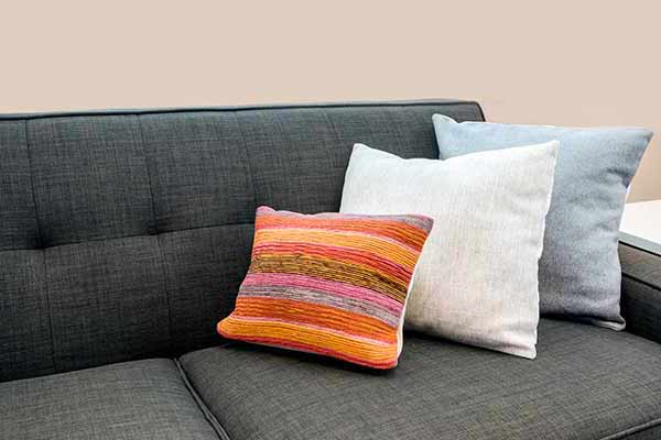 closeup of bright colored accent pillows on a black couch