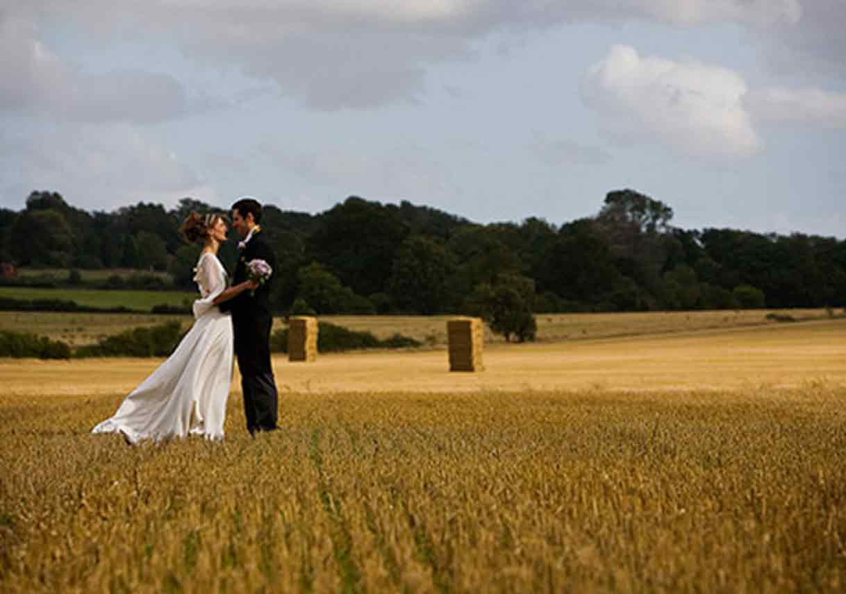 wedded couple stands in large wheat field