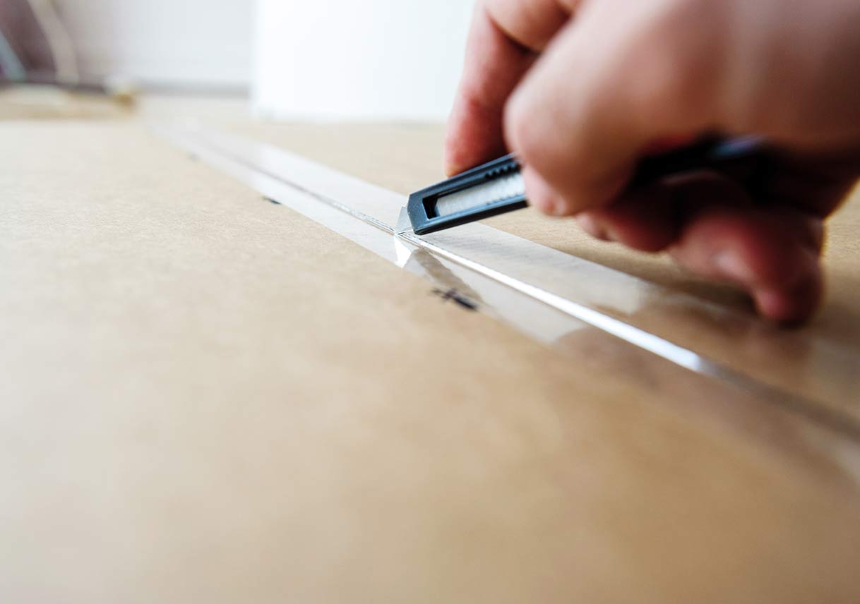 hands closing cardboard box with packing tape