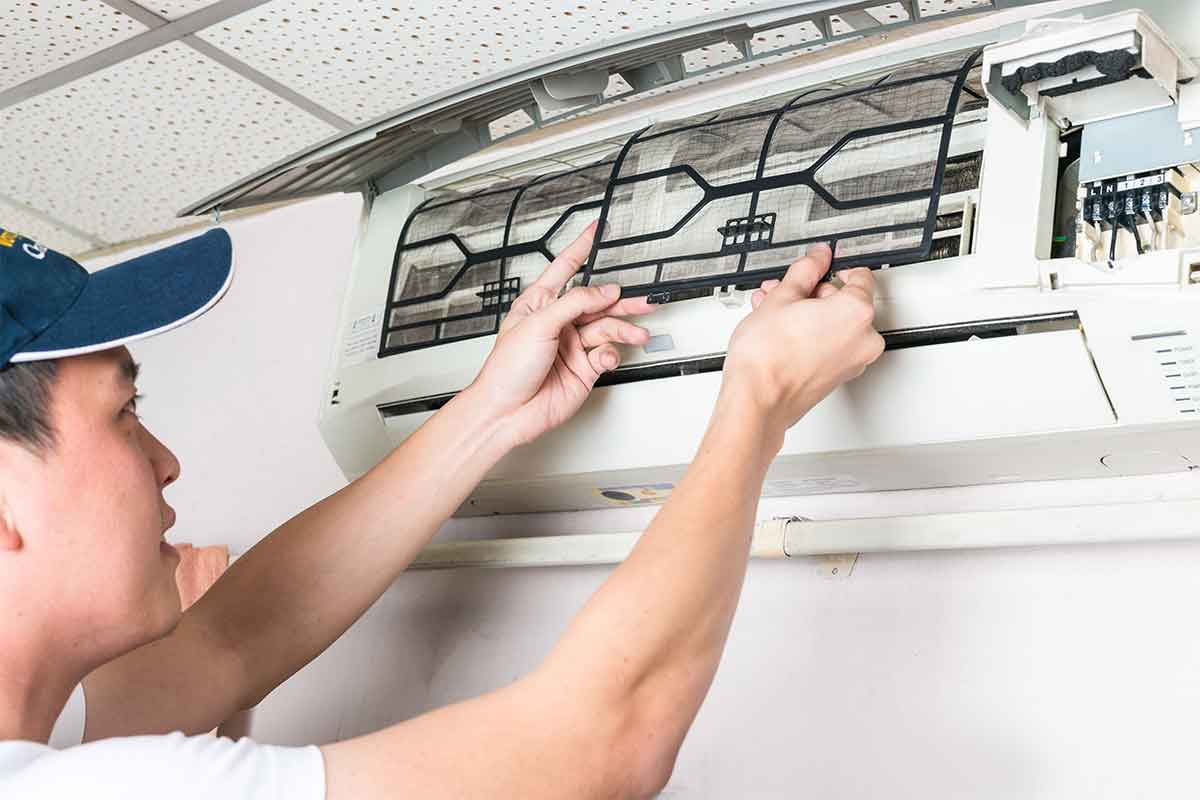 man opening air conditioning unit to clean it