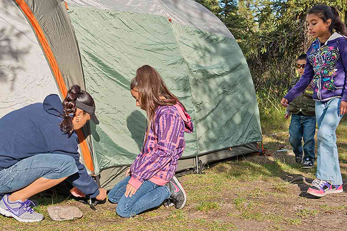 Woman setting up a tent with three children