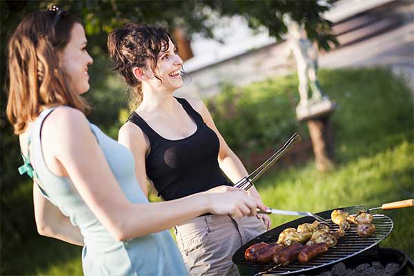 two girls cooking food on a grill