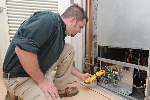 HVAC technician using a meter to check heat pump