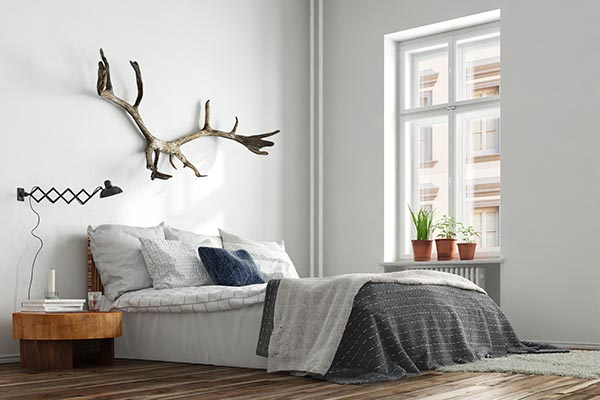 clean, modern bedroom with bed, nightstand, and antlers on wall