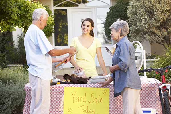 Older couple talking to Girl Holding Yard Sale