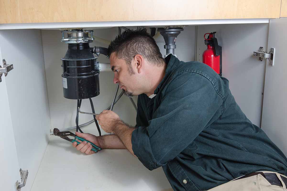 plumber fixing a garbage disposal