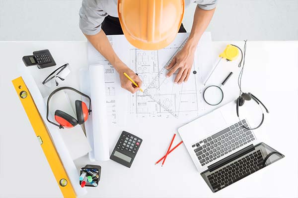 Overhead view of a man in hard hat sketching a construction project]