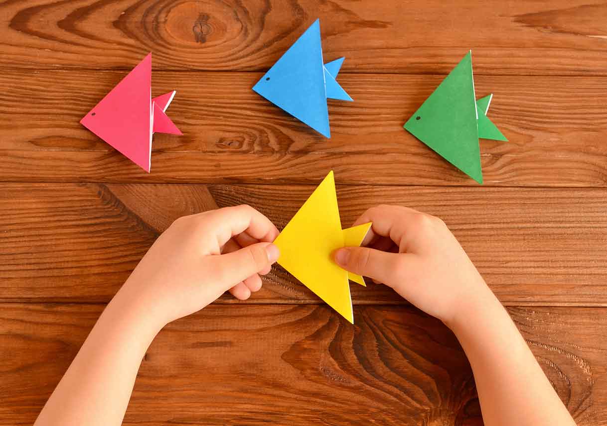 child holds origami fish