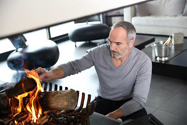 man lighting fire in indoor fireplace