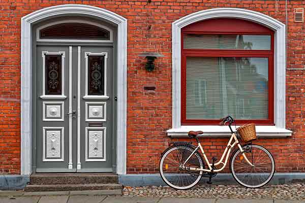 bike parked in front of brick building with grey front door with white painted accents