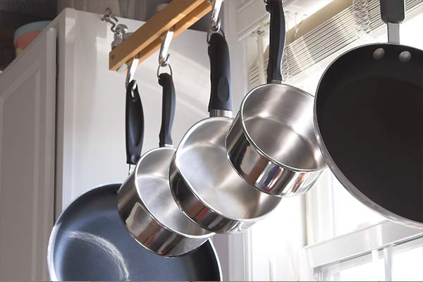 pots and pans hanging on rack in front of a window