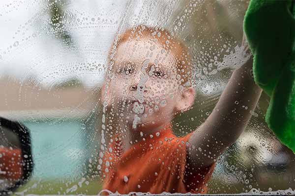 closeup of a boy washing a window