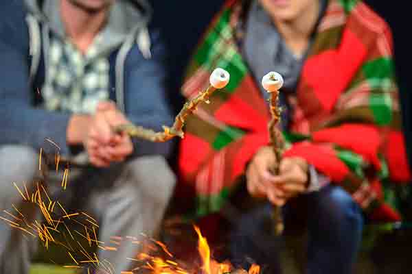 couple roasting marshmallows over a fire