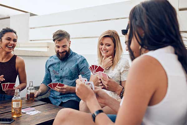 group of friends sitting at a wooden table playing cards during a party