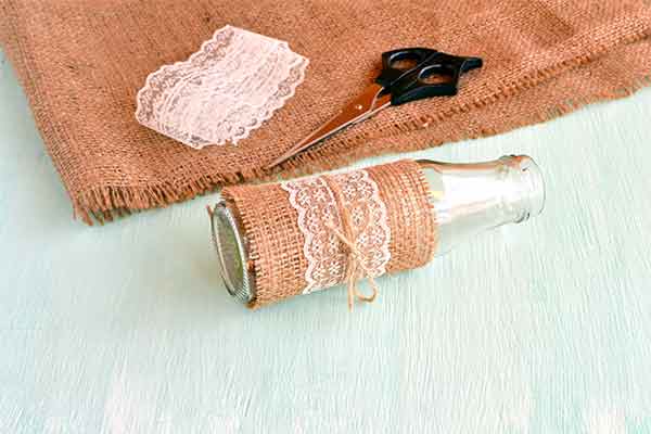 burlap with scissors and lace on top next to a crafty vase