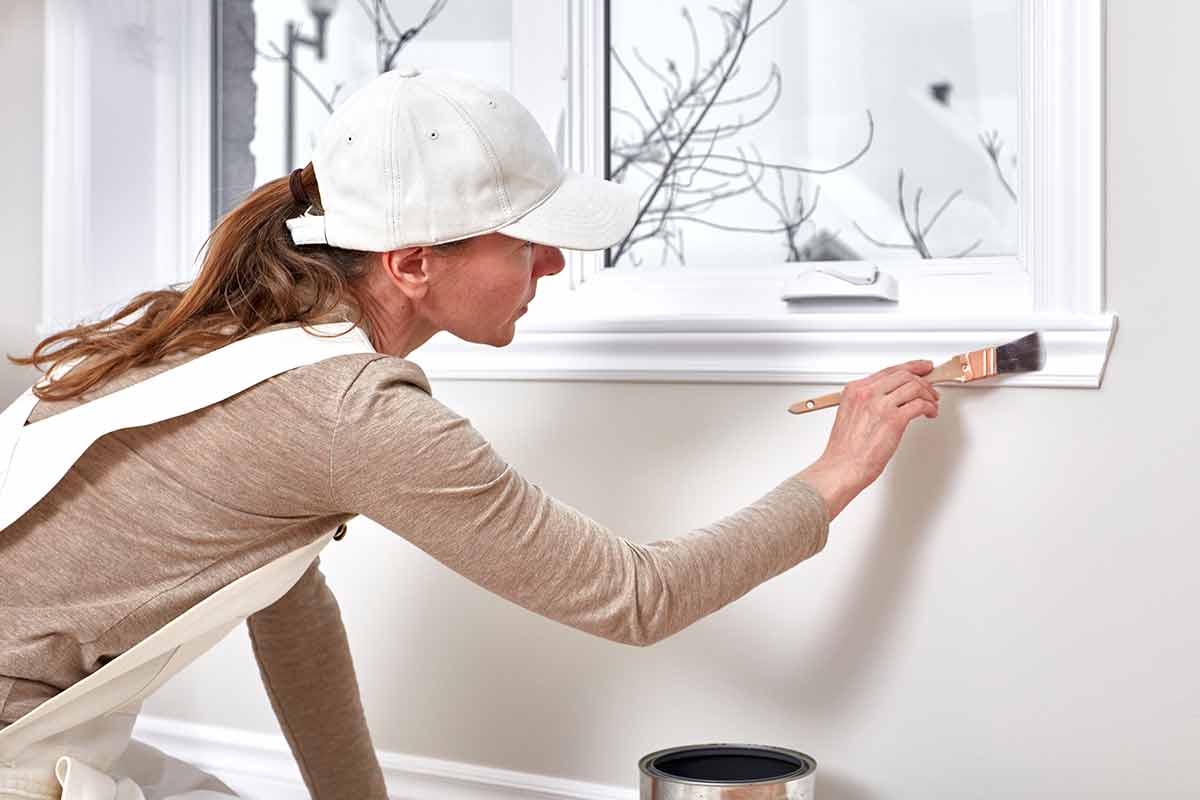 woman painting window trim with oil-based point