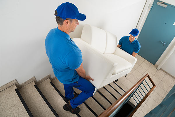 professional movers carrying sofa down set of stairs