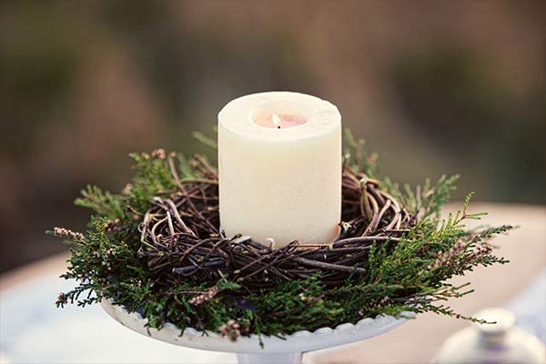 white candle wreathed with pine leafs and twigs