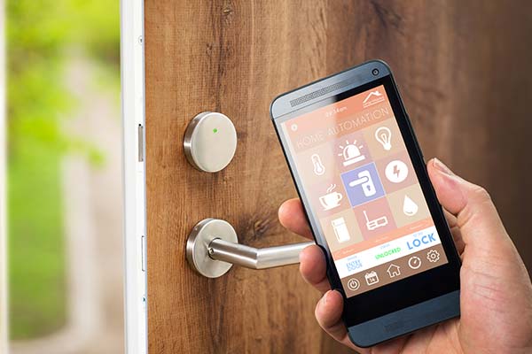 smart home app on cell phone in front of unlocked door