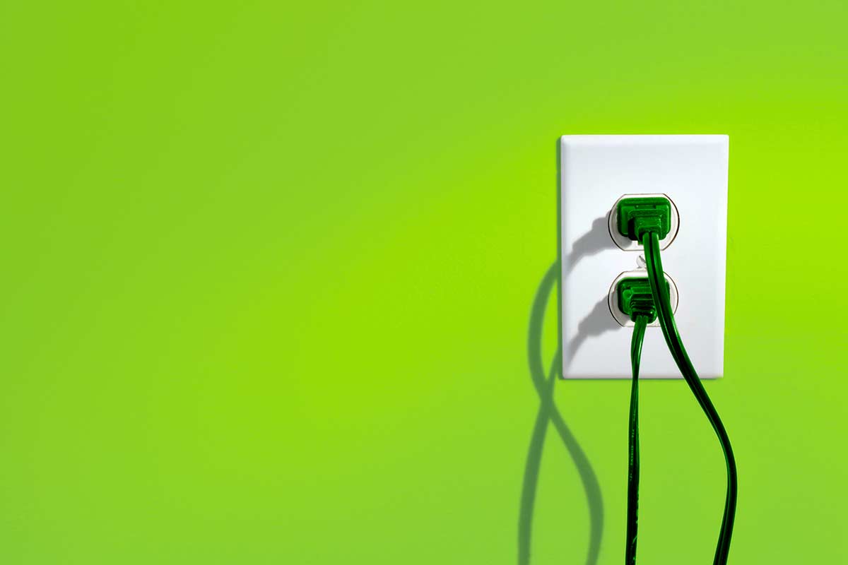 power cords plugged into outlet on a green wall