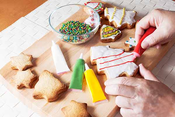 close up of hands decorating christmas cookies