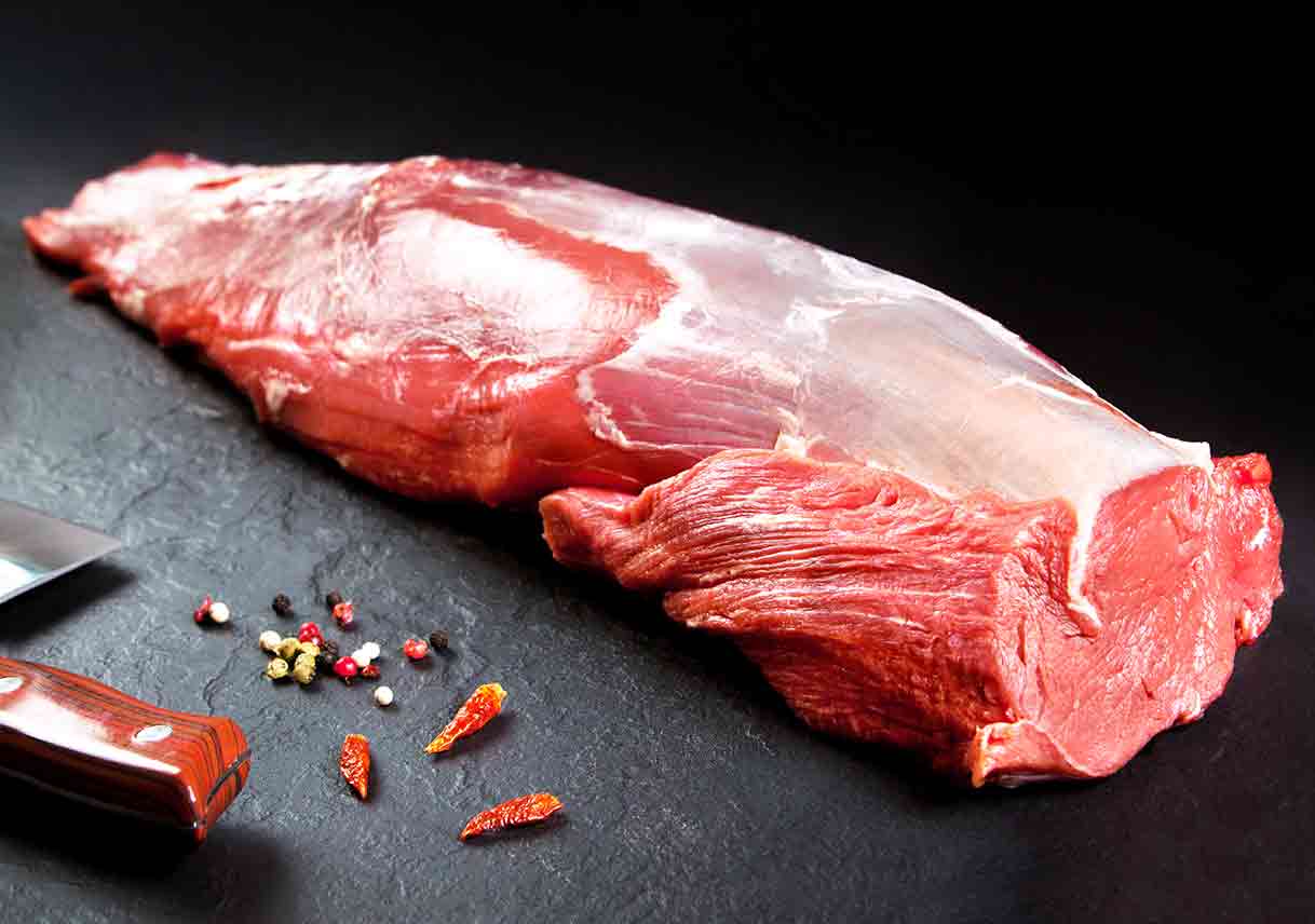 whole raw beef tenderloin on black background