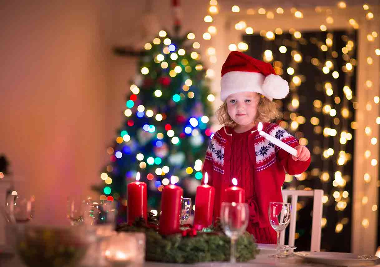 child lighting candles at Christmas table