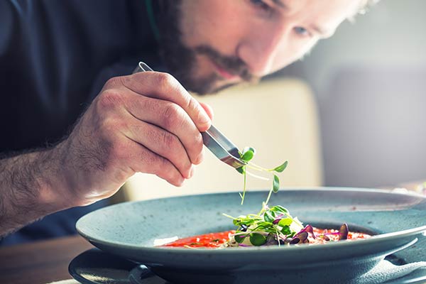 chef decorating plate with herbs