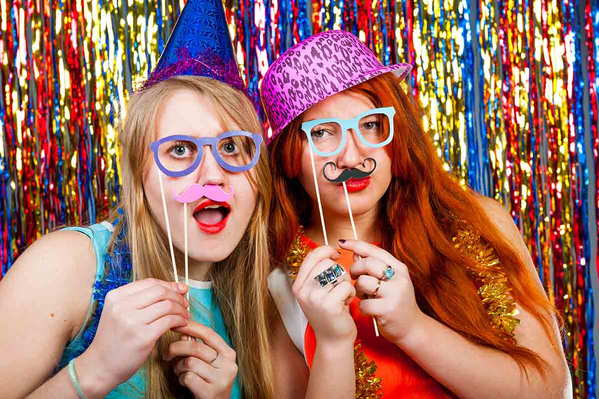 girls pose with props in a dance party photo booth