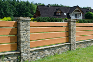 wood fence with stone posts in front of house